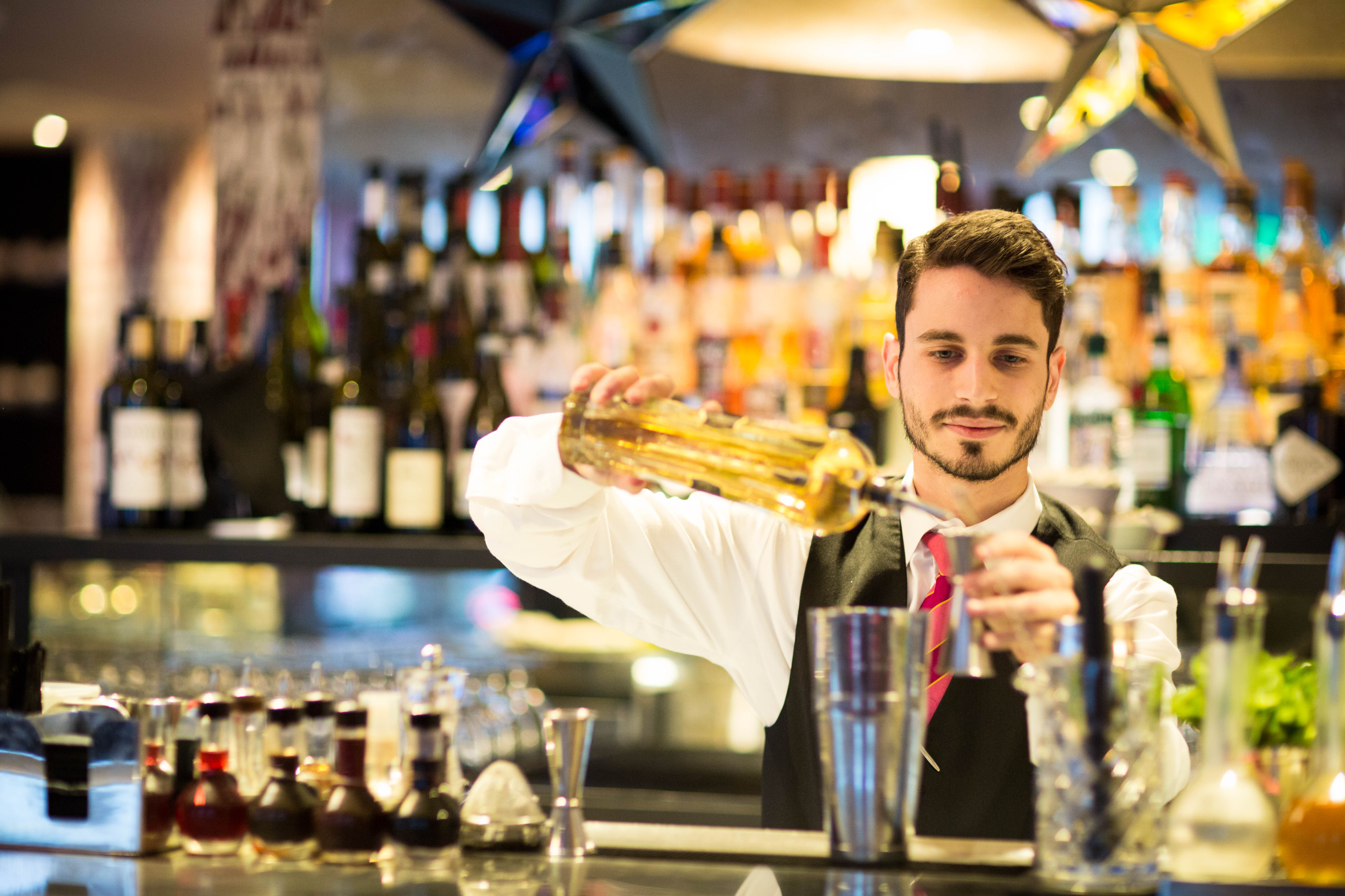 A bartender pouring a cocktail